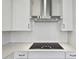 Modern kitchen featuring a stainless steel range hood, cooktop, and white subway tile backsplash at 16994 Cedar Valley Cir, Clermont, FL 34711