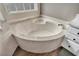 Close up on a garden tub with marble surround, window view, and adjacent vanity at 1530 The Oaks Blvd, Kissimmee, FL 34746