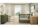 Stylish Bedroom showcasing a green crib, statement mirror, soft chair, and coordinated neutral and green accents at 2109 Lasso Loop, Eagle Lake, FL 33839