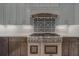 Close-up shot of a stainless steel range and hood with decorative backsplash and two-tone cabinets at 4004 Se 47Th Pl, Ocala, FL 34480