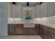 Kitchen with two-tone cabinets, white backsplash, and a farmhouse sink under a window with blind at 4004 Se 47Th Pl, Ocala, FL 34480
