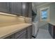 Laundry room with stone countertops, gray cabinets and new model washer and dryer at 4004 Se 47Th Pl, Ocala, FL 34480