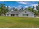 Beautiful home boasts light-green exterior, stone accents, expansive windows, and a spacious backyard perfect for outdoor enjoyment at 4004 Se 47Th Pl, Ocala, FL 34480