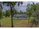 Charming home's rear facade displays light-green siding and stone foundation amidst a spacious green lawn and natural tree setting at 4004 Se 47Th Pl, Ocala, FL 34480
