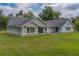 Expansive single-Gathering home features light-green siding, stone foundation, large windows, and an open-air back patio with lawn at 4004 Se 47Th Pl, Ocala, FL 34480
