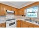 Bright kitchen featuring wooden cabinets, stainless steel sink, and standard white appliances at 1123 Enchanted Dr, Lakeland, FL 33801