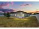 Backyard at twilight featuring a covered patio, green lawn, and white fencing at 921 Fieldstone Way, Haines City, FL 33844