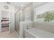 Bathroom featuring a glass-enclosed shower, separate tub, and window at 921 Fieldstone Way, Haines City, FL 33844