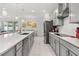 Kitchen features stainless steel appliances, quartz countertops, gray cabinets, and an island with barstool seating at 921 Fieldstone Way, Haines City, FL 33844