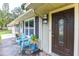 Charming front porch featuring slate flooring and two blue Adirondack chairs near the decorative glass-paneled front door at 781 Little Pine Dr, South Daytona, FL 32119