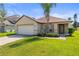 Well-kept single-Gathering home boasts a manicured lawn, mature tree, and two-car garage at 358 Canna Dr, Davenport, FL 33897