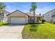 Inviting home with a well-maintained lawn, attached garage, and mature palm tree at 358 Canna Dr, Davenport, FL 33897