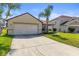 Attractive one-story home with a two-car garage, lush green lawn, and sidewalk at 358 Canna Dr, Davenport, FL 33897