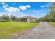 Spacious backyard with lush green lawn, screened-in porch, and gravel driveway leading to the home at 3979 Mammoth Grove Rd, Lake Wales, FL 33898