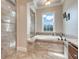 Luxurious bathroom features a soaking tub, glass-enclosed shower, and travertine tile surround at 3979 Mammoth Grove Rd, Lake Wales, FL 33898