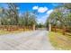 Long gravel driveway leading to home with wood fence and iron gate at 3979 Mammoth Grove Rd, Lake Wales, FL 33898