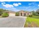 Beautiful single-story home features a two-car garage, archway entrance, and manicured landscaping with vibrant flowers and palm trees at 3979 Mammoth Grove Rd, Lake Wales, FL 33898