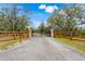 Gated entrance flanked by wooden fencing and mature trees creates privacy and security for this estate at 3979 Mammoth Grove Rd, Lake Wales, FL 33898