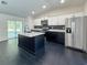 Modern kitchen with a contrasting black island, stainless steel appliances, and sleek dark floors at 481 S East Ave, Bartow, FL 33830
