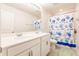 Clean bathroom with a double sink vanity, shower with a blue turtle-themed curtain, and modern finishes at 1123 Sugarwood St, Davenport, FL 33837