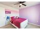 This cozy bedroom has a ceiling fan, plush carpeting, and a pink and white striped accent wall at 1123 Sugarwood St, Davenport, FL 33837