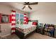 A stylish bedroom with red and white striped curtains, dinosaur themed bedding, and a ceiling fan at 1123 Sugarwood St, Davenport, FL 33837