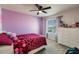 Bright bedroom featuring a ceiling fan, a window with blinds, and a purple painted accent wall at 1123 Sugarwood St, Davenport, FL 33837