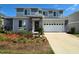 Two-story home featuring a two-car garage, stone accents, and neatly landscaped front yard at 1123 Sugarwood St, Davenport, FL 33837
