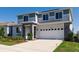 Charming two-story home with gray and white facade, stone accents, and well-maintained landscaping at 1123 Sugarwood St, Davenport, FL 33837
