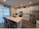 Bright kitchen featuring white cabinets, stainless steel appliances, and a large island with seating at 1123 Sugarwood St, Davenport, FL 33837