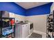 Efficient laundry room with modern washer and dryer, shelving for storage, and blue and gray painted walls at 1123 Sugarwood St, Davenport, FL 33837