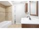 Bathroom features a tiled shower and bathtub combination, vanity, wall cabinet, and neutral-toned tile flooring at 5926 N Fork Ct, Lakeland, FL 33809