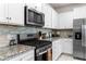 Close up view of a kitchen showing granite counters, stainless steel appliances, and sleek tile backsplash at 7614 Oak Spring Ln, Davenport, FL 33837