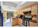 Traditional-style kitchen featuring natural wood cabinets and black appliances with access to the backyard patio at 4836 Pebble Beach Dr, Orlando, FL 32811