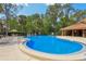 Community pool with surrounding lounge chairs and a cabana in the background amid mature trees at 4836 Pebble Beach Dr, Orlando, FL 32811