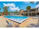 Community pool with seating areas, perfect for hot summer days; tennis courts and community building in the background at 4836 Pebble Beach Dr, Orlando, FL 32811