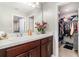 Bathroom featuring double sinks with dark wood cabinetry, a white countertop, and an overflowing walk-in closet at 6889 Wilson Hammock Ave, Groveland, FL 34736
