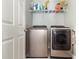 Modern laundry room featuring stainless steel washer and dryer, with storage shelf above at 6889 Wilson Hammock Ave, Groveland, FL 34736