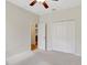 A clean bedroom featuring a ceiling fan, carpet flooring, and a closet with louvered doors at 13708 Old Dock Rd, Orlando, FL 32828