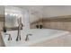 Close up view of a luxurious soaking tub with tile surround and modern faucet at 3550 Rodrick Cir, Orlando, FL 32824