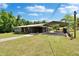 Wide angle shot of a gray brick home with a matching carport, surrounded by a spacious green lawn at 4145 Willow Oak Rd, Mulberry, FL 33860