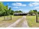 Grey one story home, featuring a spacious yard, carport, and fenced entry on a sunny day at 4145 Willow Oak Rd, Mulberry, FL 33860