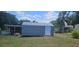 Exterior view of a gray shed with a white door situated in a grassy backyard, offering outdoor storage at 4145 Willow Oak Rd, Mulberry, FL 33860