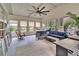 Bright sunroom featuring a wicker sofa, ceiling fan, and views of the landscaped backyard at 4145 Willow Oak Rd, Mulberry, FL 33860