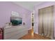 Light-filled bedroom features purple walls, wood flooring, and neutral-toned dresser with TV at 455 W Plumosa St, Bartow, FL 33830