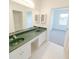 Bathroom featuring a double vanity with green countertops and white cabinets and white tile floor at 6354 Sedgeford Dr, Lakeland, FL 33811
