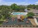 An aerial view showcasing the community pool, playground, pond, and surrounding trees at 6523 Evergreen Park Dr, Lakeland, FL 33813