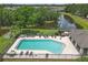 Aerial view of a community pool surrounded by lounge chairs, trees, and nearby water feature at 6523 Evergreen Park Dr, Lakeland, FL 33813