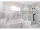 A luxurious bathroom showcasing a soaking tub and a glass-enclosed shower with elegant marble-style tiling at 2721 Stonewood Dr, Lakeland, FL 33810