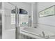 A bright white tiled tub next to a shower featuring glass block and silver plumbing at 6442 Bendelow Dr, Lakeland, FL 33810
